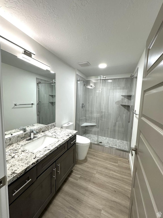1189 E Benchview Dr, Ogden, UT 84404 - full bathroom with vanity, a stall shower, a textured ceiling, toilet, and wood finished floors