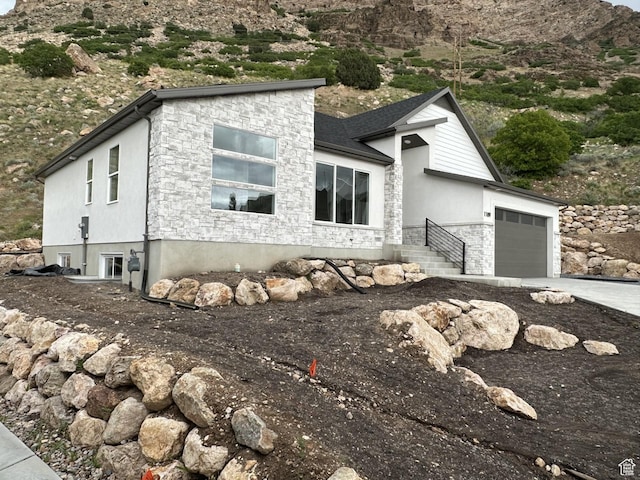 1189 E Benchview Dr, Ogden, UT 84404 - view of front facade with stone siding, an attached garage, driveway, and stucco siding