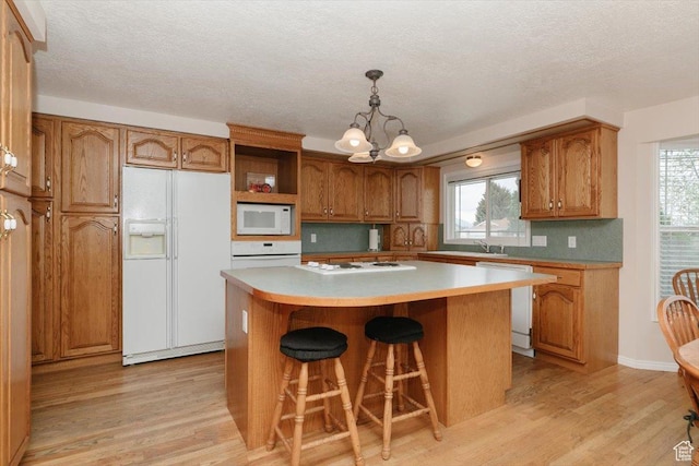 310 E Valley View Dr, Preston, ID 83263 - kitchen with white appliances, light wood-type flooring, brown cabinetry, and a textured ceiling