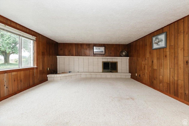 310 E Valley View Dr, Preston, ID 83263 - unfurnished living room featuring wood walls, a textured ceiling, carpet, a brick fireplace, and baseboards