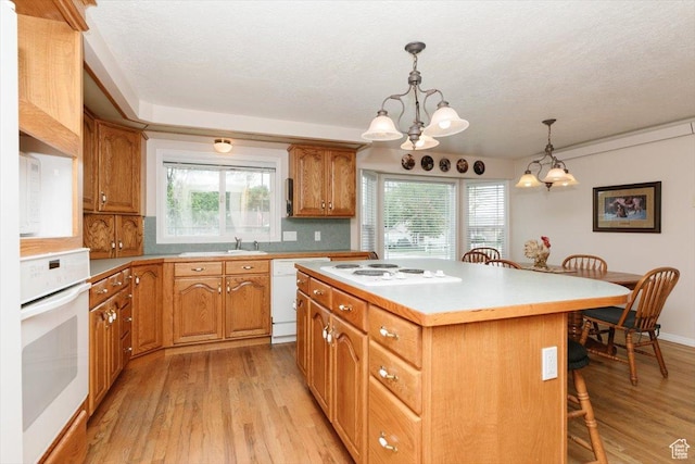 310 E Valley View Dr, Preston, ID 83263 - kitchen featuring white appliances, a kitchen breakfast bar, a center island, light wood-style floors, and a textured ceiling