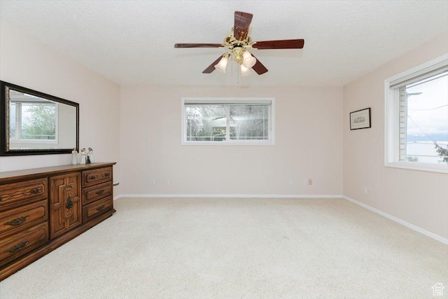 310 E Valley View Dr, Preston, ID 83263 - unfurnished bedroom with light carpet, multiple windows, baseboards, a ceiling fan, and a textured ceiling