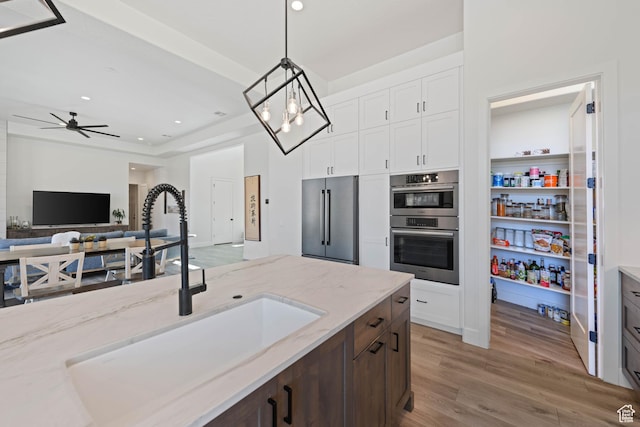 108 N Arrowhead Ln, Ivins, UT 84738 - kitchen with appliances with stainless steel finishes, a sink, light stone counters, wood finished floors, and pendant lighting