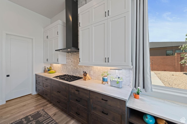 108 N Arrowhead Ln, Ivins, UT 84738 - kitchen with wall chimney range hood, black gas stovetop, backsplash, light wood-style flooring, and white cabinetry