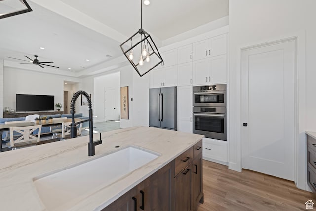 108 N Arrowhead Ln, Ivins, UT 84738 - kitchen featuring appliances with stainless steel finishes, a sink, wood finished floors, light stone countertops, and decorative light fixtures