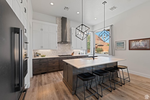 108 N Arrowhead Ln, Ivins, UT 84738 - kitchen with high quality fridge, a sink, wall chimney range hood, stainless steel gas cooktop, and white cabinetry