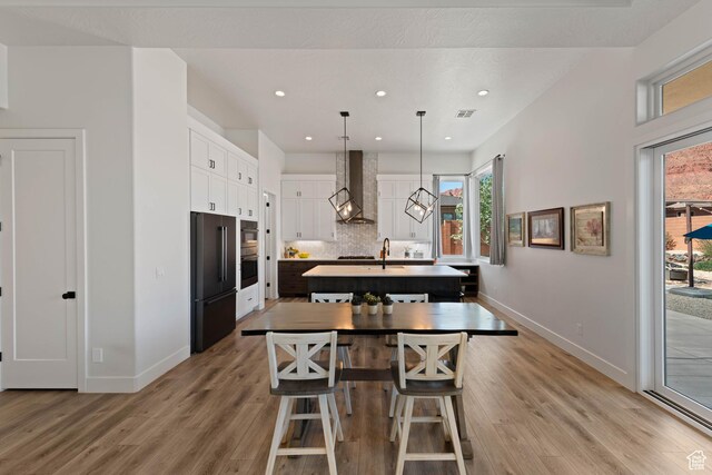 108 N Arrowhead Ln, Ivins, UT 84738 - kitchen featuring high quality fridge, wall chimney range hood, baseboards, an island with sink, and recessed lighting