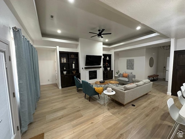 2786 S 3780 W, Hurricane, UT 84737 - living room featuring ceiling fan, light wood finished floors, a tray ceiling, a tile fireplace, and recessed lighting