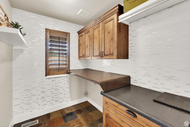 4836 S 5050 W, Hooper, UT 84315 - kitchen featuring dark countertops, baseboards, brown cabinetry, and dark stone finish floors