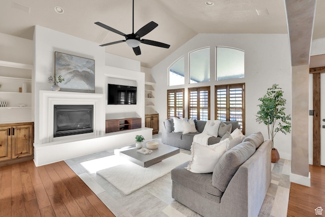 4836 S 5050 W, Hooper, UT 84315 - living room featuring a glass covered fireplace, built in shelves, light wood finished floors, ceiling fan, and high vaulted ceiling