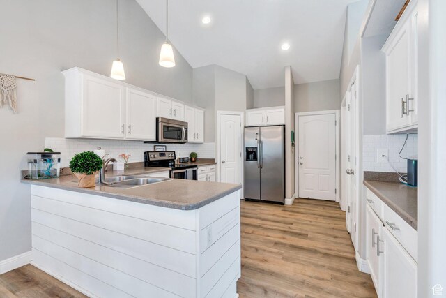 7371 N Ute Dr, Eagle Mountain, UT 84005 - kitchen featuring stainless steel appliances, a sink, a peninsula, backsplash, and high vaulted ceiling