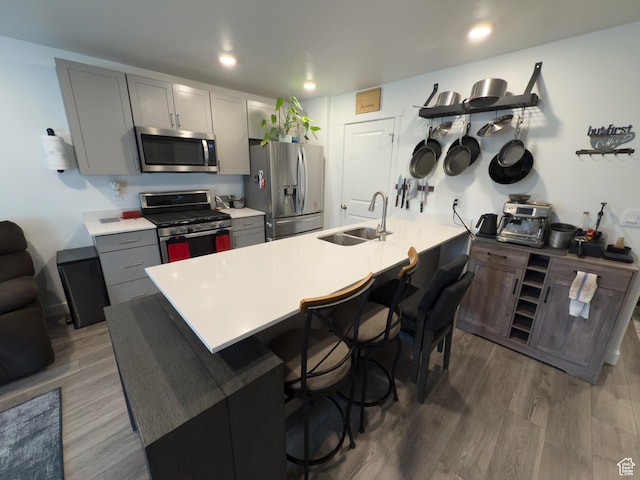 1764 E Fall St, Eagle Mountain, UT 84005 - kitchen featuring stainless steel appliances, a sink, a kitchen breakfast bar, gray cabinets, and wood finished floors