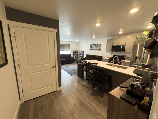 1764 E Fall St, Eagle Mountain, UT 84005 - kitchen with stainless steel appliances, a breakfast bar area, light countertops, a sink, and dark wood-type flooring