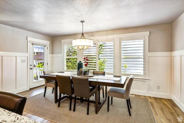 2548 E Ember Dr, Draper Ut Cnty, UT 84020 - dining room with a decorative wall, a textured ceiling, wainscoting, a chandelier, and light wood-style flooring