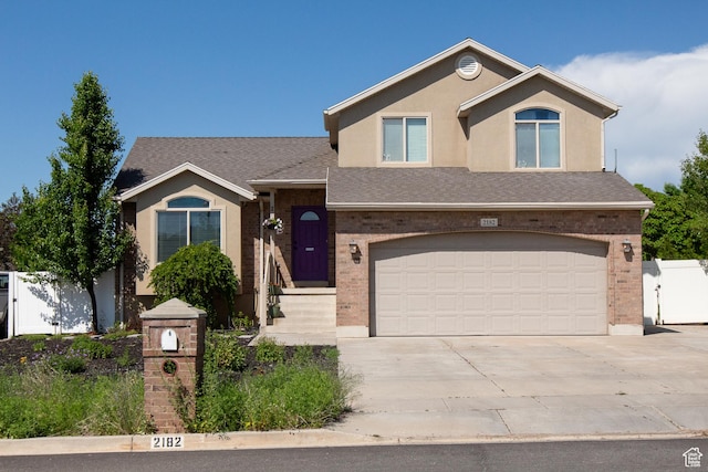 2182 W 1145 N, Clinton, UT 84015 - view of front facade featuring concrete driveway, an attached garage, brick siding, roof with shingles, and stucco siding