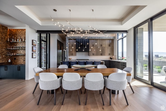 7744 E Moon Dance Cir, Kamas, UT 84036 - dining room with a raised ceiling, plenty of natural light, light wood finished floors, and a chandelier