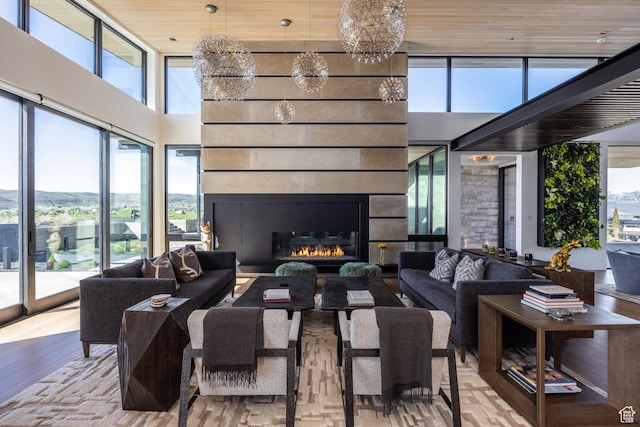 7744 E Moon Dance Cir, Kamas, UT 84036 - living room featuring wood finished floors, a towering ceiling, a chandelier, and a glass covered fireplace