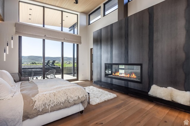 7744 E Moon Dance Cir, Kamas, UT 84036 - bedroom featuring a high ceiling, access to outside, wood finished floors, a glass covered fireplace, and a mountain view