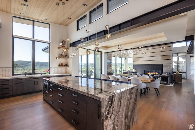 7744 E Moon Dance Cir, Kamas, UT 84036 - kitchen with hardwood / wood-style floors, dark brown cabinetry, tasteful backsplash, a kitchen island, and light stone counters