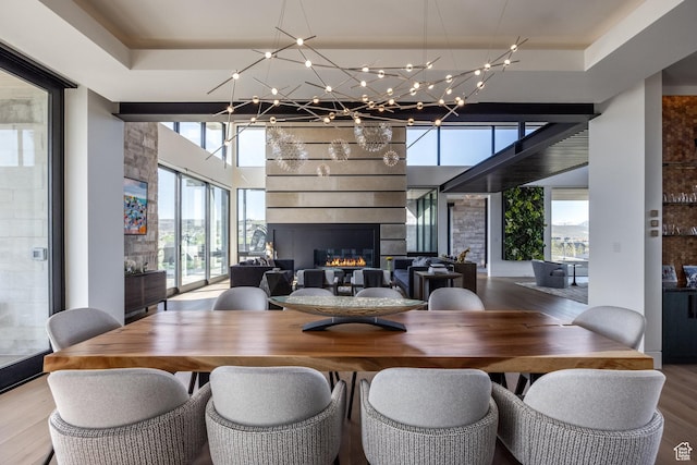 7744 E Moon Dance Cir, Kamas, UT 84036 - dining room with wood finished floors, a large fireplace, a chandelier, and a raised ceiling