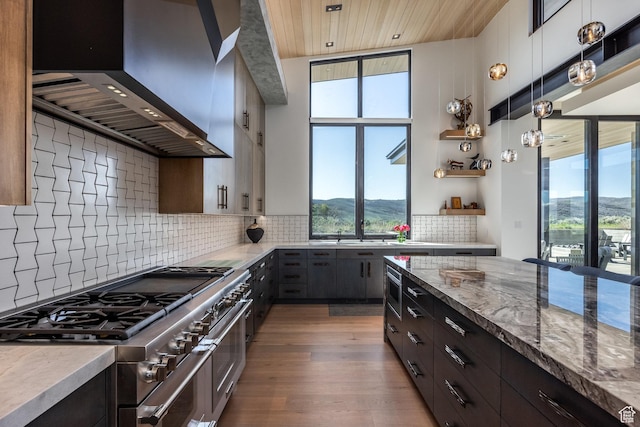 7744 E Moon Dance Cir, Kamas, UT 84036 - kitchen with range with two ovens, wall chimney range hood, healthy amount of natural light, wood finished floors, and recessed lighting