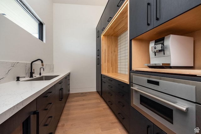 7744 E Moon Dance Cir, Kamas, UT 84036 - kitchen featuring stainless steel oven, a sink, backsplash, light wood-style floors, and light countertops
