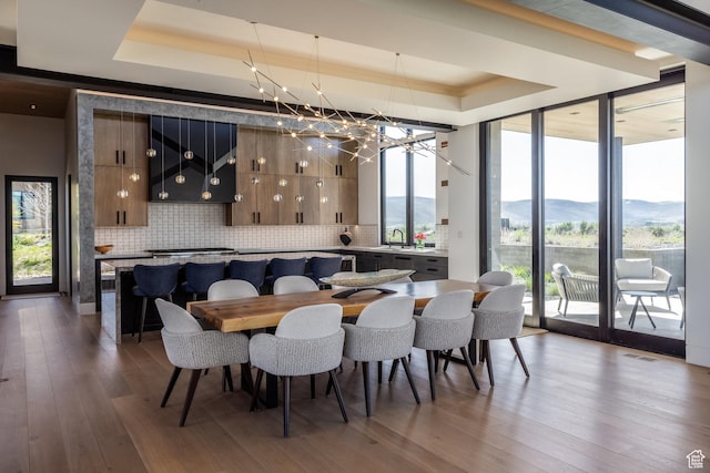 7744 E Moon Dance Cir, Kamas, UT 84036 - dining space featuring a raised ceiling, wood finished floors, a chandelier, expansive windows, and a mountain view