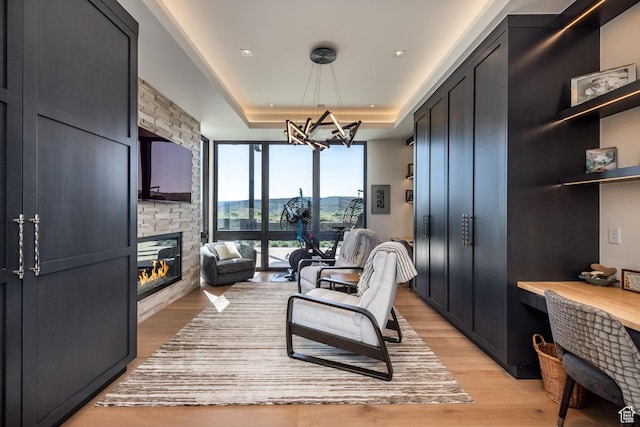 7744 E Moon Dance Cir, Kamas, UT 84036 - living area featuring a large fireplace, light wood finished floors, a chandelier, and a tray ceiling
