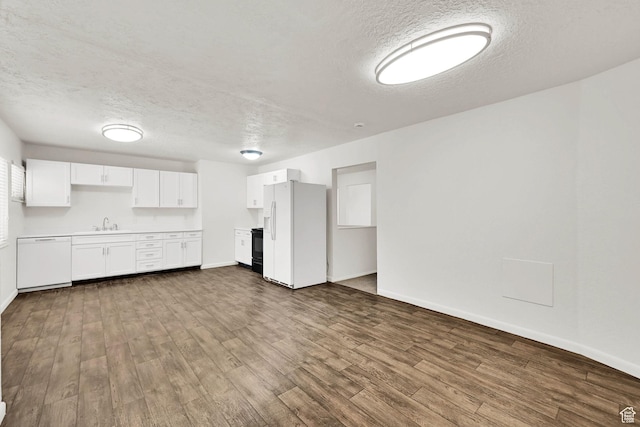 10679 S 2200 W, South Jordan, UT 84095 - unfurnished living room featuring a textured ceiling, dark wood finished floors, baseboards, and a sink