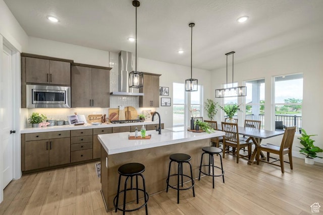 1104 N Windflower Ln Unit 127, Grantsville, UT 84029 - kitchen with wall chimney range hood, stainless steel microwave, light countertops, a breakfast bar area, and light wood-style flooring