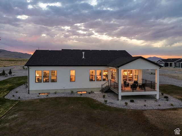 1104 N Windflower Ln Unit 127, Grantsville, UT 84029 - back of property at dusk with a lawn, a wooden deck, and stucco siding