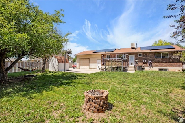 587 W 1460 N, Clinton, UT 84015 - rear view of house with a garage, roof mounted solar panels, an outdoor fire pit, concrete driveway, and cooling unit