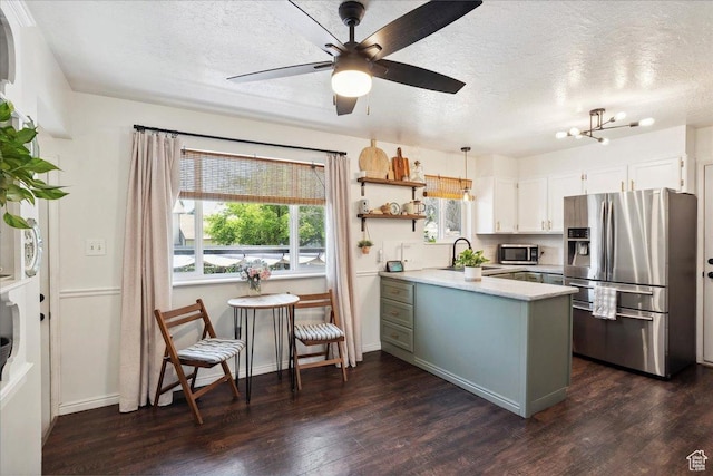 587 W 1460 N, Clinton, UT 84015 - kitchen with appliances with stainless steel finishes, a peninsula, a textured ceiling, light countertops, and dark wood-type flooring