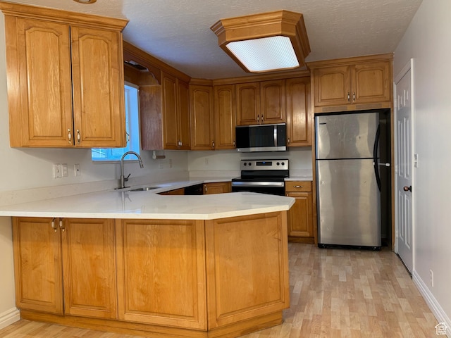 4440 W 6095 S, Taylorsville, UT 84118 - kitchen featuring appliances with stainless steel finishes, a sink, a peninsula, light wood-style flooring, and light countertops