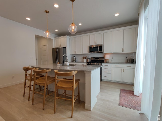 2132 N Elderberry Dr W, Saratoga Springs, UT 84045 - kitchen with stainless steel appliances, light wood finished floors, a center island with sink, backsplash, and recessed lighting