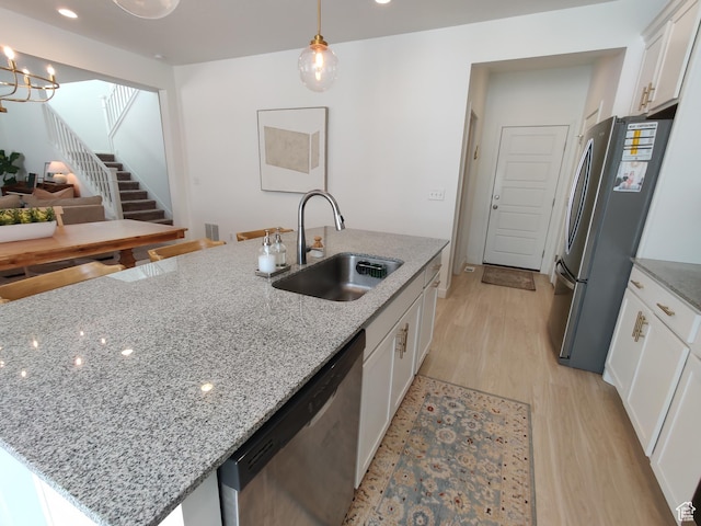 2132 N Elderberry Dr W, Saratoga Springs, UT 84045 - kitchen featuring stainless steel appliances, a sink, light wood-style flooring, white cabinets, and a center island with sink