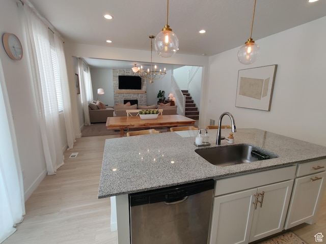 2132 N Elderberry Dr W, Saratoga Springs, UT 84045 - kitchen with stainless steel dishwasher, a sink, a large fireplace, a center island with sink, and light wood-type flooring