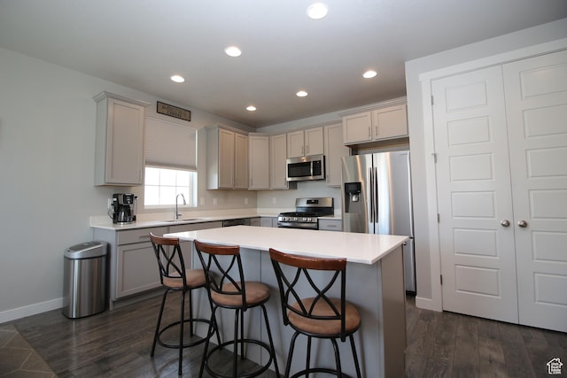 1457 W 400 S, Syracuse, UT 84075 - kitchen with appliances with stainless steel finishes, a sink, a breakfast bar area, dark wood finished floors, and light countertops