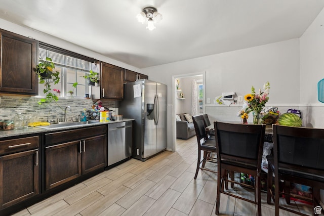 2120 Pingree Ave, Ogden, UT 84401 - kitchen featuring stainless steel appliances, dark brown cabinets, a sink, decorative backsplash, and light wood-style flooring