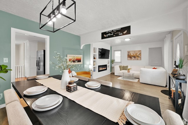 2883 S Brinker Ave E, Ogden, UT 84403 - dining space featuring wood finished floors, a textured ceiling, a glass covered fireplace, built in shelves, and baseboards