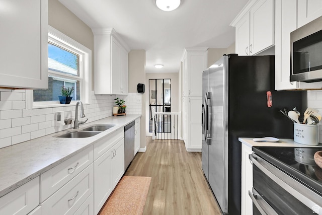 2883 S Brinker Ave E, Ogden, UT 84403 - kitchen featuring a sink, stainless steel appliances, white cabinetry, and backsplash