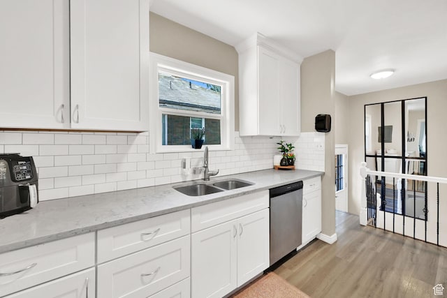 2883 S Brinker Ave E, Ogden, UT 84403 - kitchen featuring dishwasher, a sink, light wood-style flooring, white cabinetry, and decorative backsplash