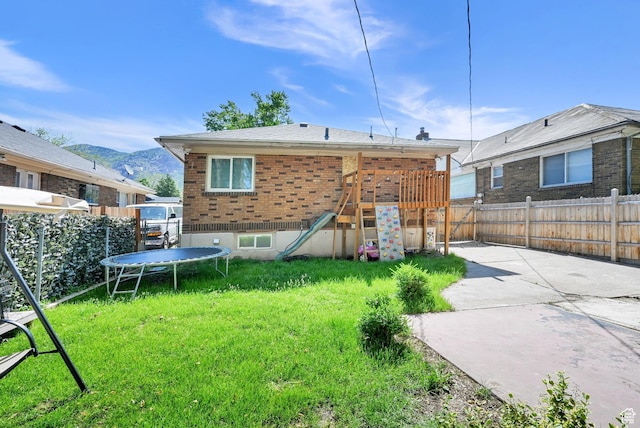 2883 S Brinker Ave E, Ogden, UT 84403 - rear view of house featuring a trampoline, a patio area, brick siding, and a mountain view