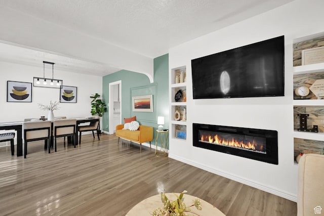 2883 S Brinker Ave E, Ogden, UT 84403 - living room featuring a glass covered fireplace, wood finished floors, built in features, baseboards, and a textured ceiling