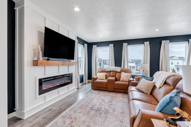 6439 W S Jordan Pkwy, South Jordan, UT 84009 - living area with a textured ceiling, a glass covered fireplace, wood finished floors, recessed lighting, and baseboards