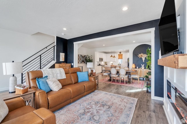 6439 W S Jordan Pkwy, South Jordan, UT 84009 - living room featuring light wood-style flooring, stairs, baseboards, a glass covered fireplace, and recessed lighting