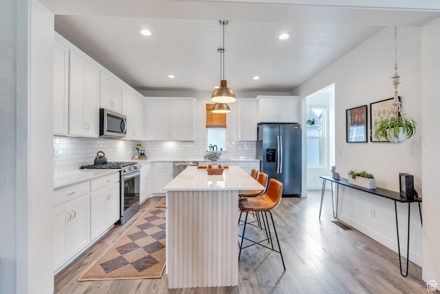 6439 W S Jordan Pkwy, South Jordan, UT 84009 - kitchen featuring stainless steel appliances, a breakfast bar, light countertops, backsplash, and light wood-style flooring