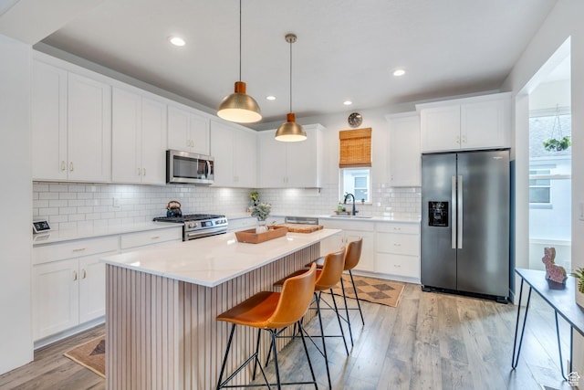 6439 W S Jordan Pkwy, South Jordan, UT 84009 - kitchen with stainless steel appliances, light wood-type flooring, a kitchen breakfast bar, light countertops, and decorative backsplash