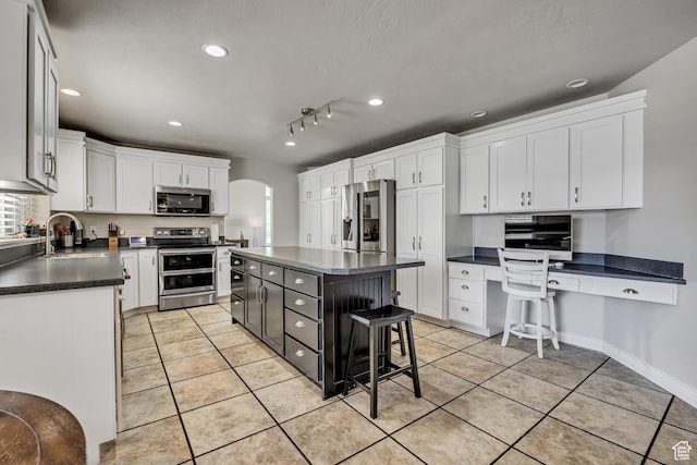 1162 E 1180 N, American Fork, UT 84003 - kitchen with stainless steel appliances, dark countertops, arched walkways, light tile patterned flooring, and white cabinets