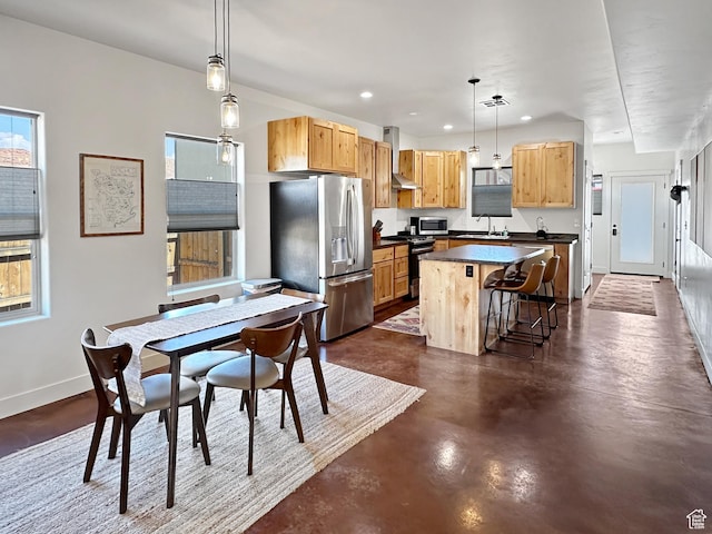 1005 S Valley View Ct, Moab, UT 84532 - kitchen with stainless steel appliances, a center island, dark countertops, wall chimney range hood, and a kitchen bar